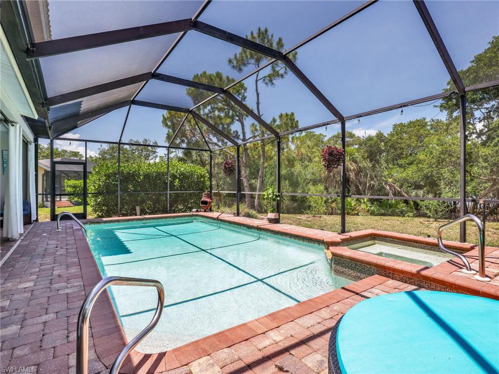 Screened lanai featuring a swimming pool, integrated spa with mosaic tile, and paver decking