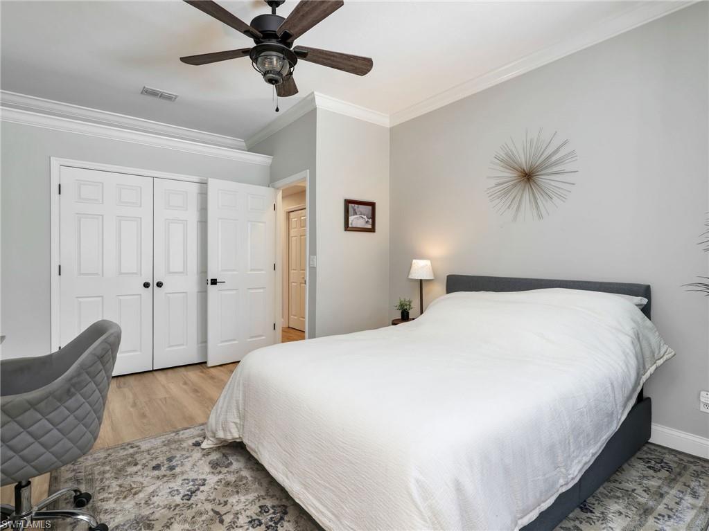 Bedroom featuring crown molding, light wood-finish flooring, and a dark wood ceiling fan