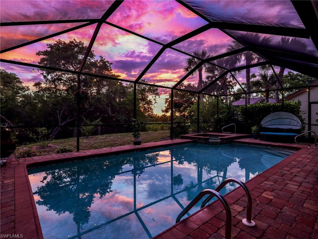 Screened outdoor pool with integrated spa and brick paver surround