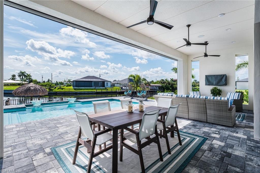 Expansive covered patio featuring a paver deck, multiple ceiling fans, and an integrated swimming pool with a waterfront setting