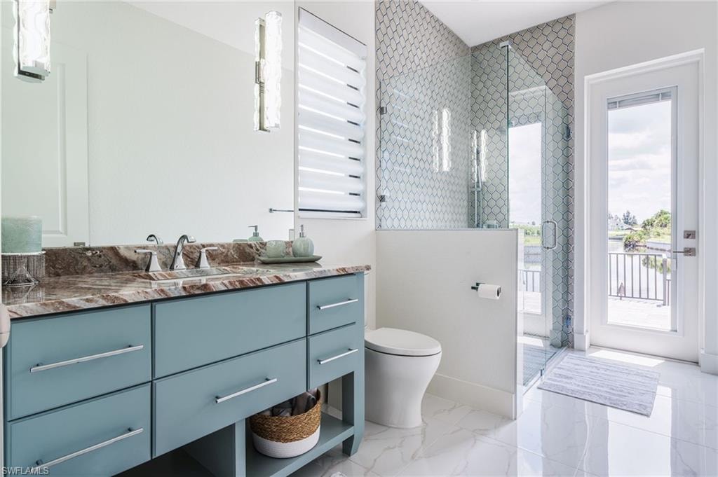 Pool bathroom featuring a dual-sink vanity with a patterned countertop, a glass-enclosed shower with tiled walls