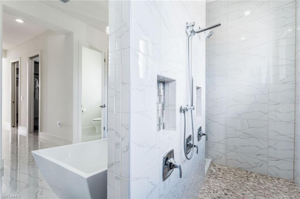 Spacious bathroom featuring a freestanding soaking tub and a walk-in shower with pebble flooring