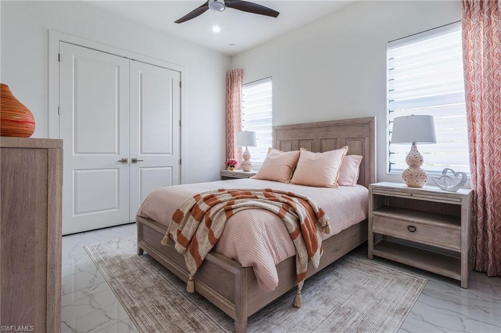 Guest bedroom featuring a ceiling fan, white paneled doors, and two windows with blinds