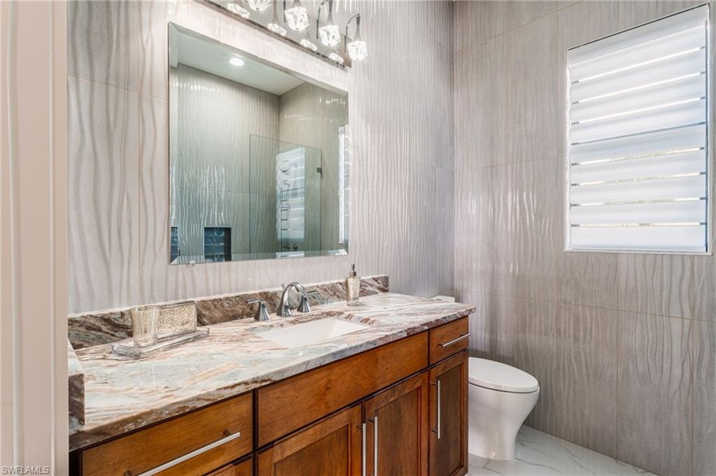 Guest bathroom featuring a wood vanity with a stone countertop, an undermount sink, and a framed mirror