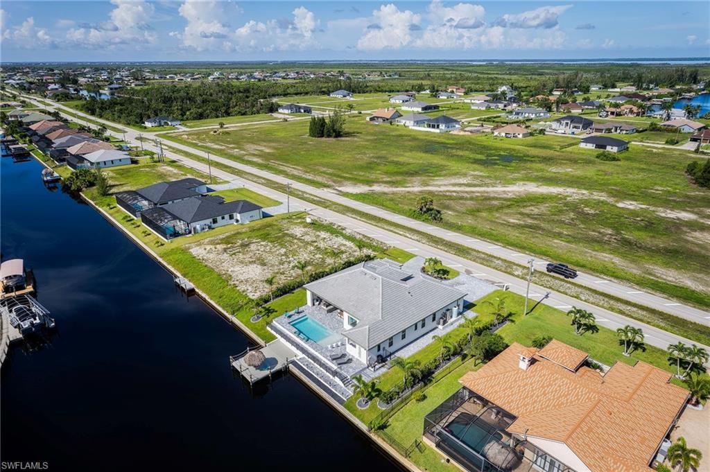 Canal-front property featuring a private dock, swimming pool, and paved patio