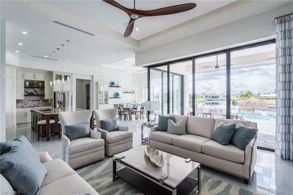 Open-concept living area with large format tile flooring, a dark wood-finish ceiling fan, and recessed lighting