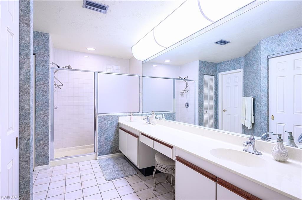 Bathroom with tile patterned flooring, vanity, and a shower with door