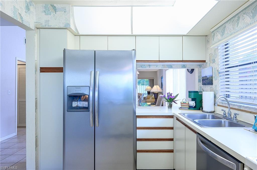 Kitchen featuring white cabinets, appliances with stainless steel finishes, light tile patterned floors, and sink