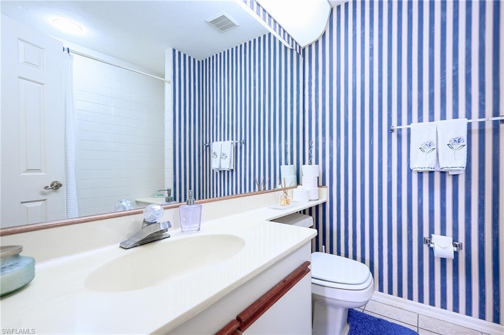 Bathroom with tile patterned flooring, vanity, tiled shower, and toilet