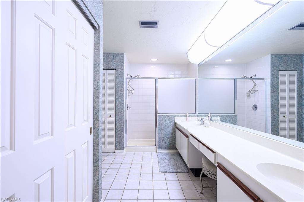 Bathroom featuring tile patterned flooring, vanity, tiled shower, and tile walls
