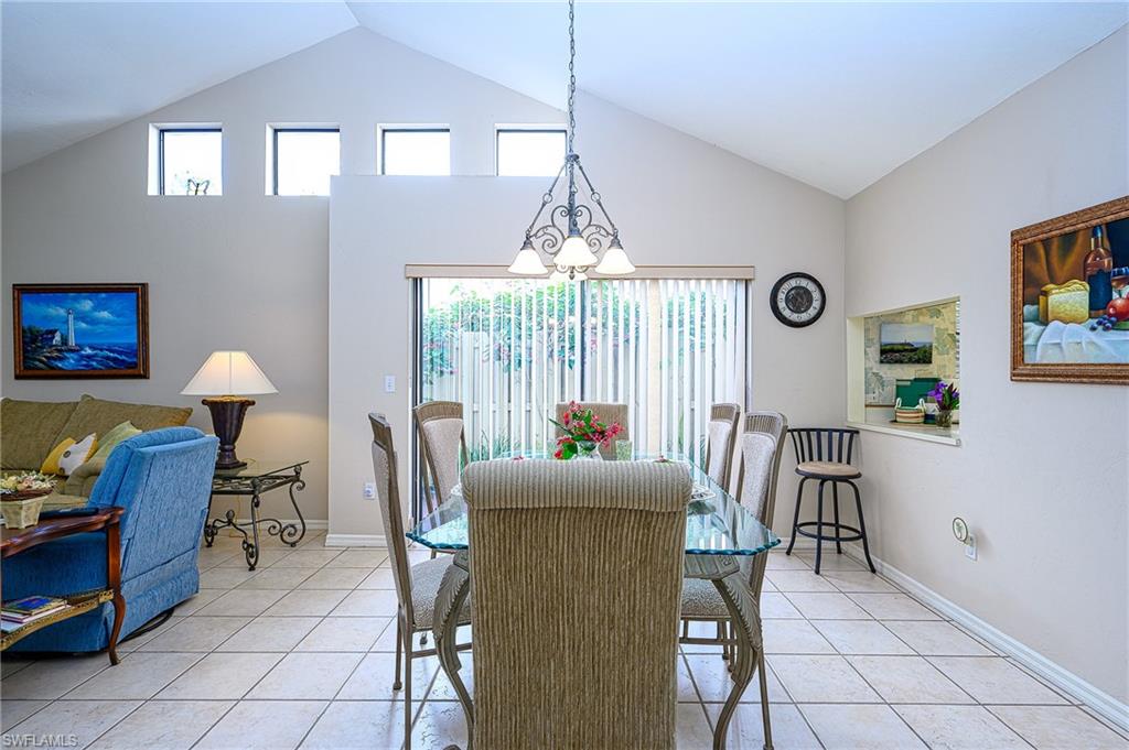 Tiled dining area featuring vaulted ceiling and a notable chandelier