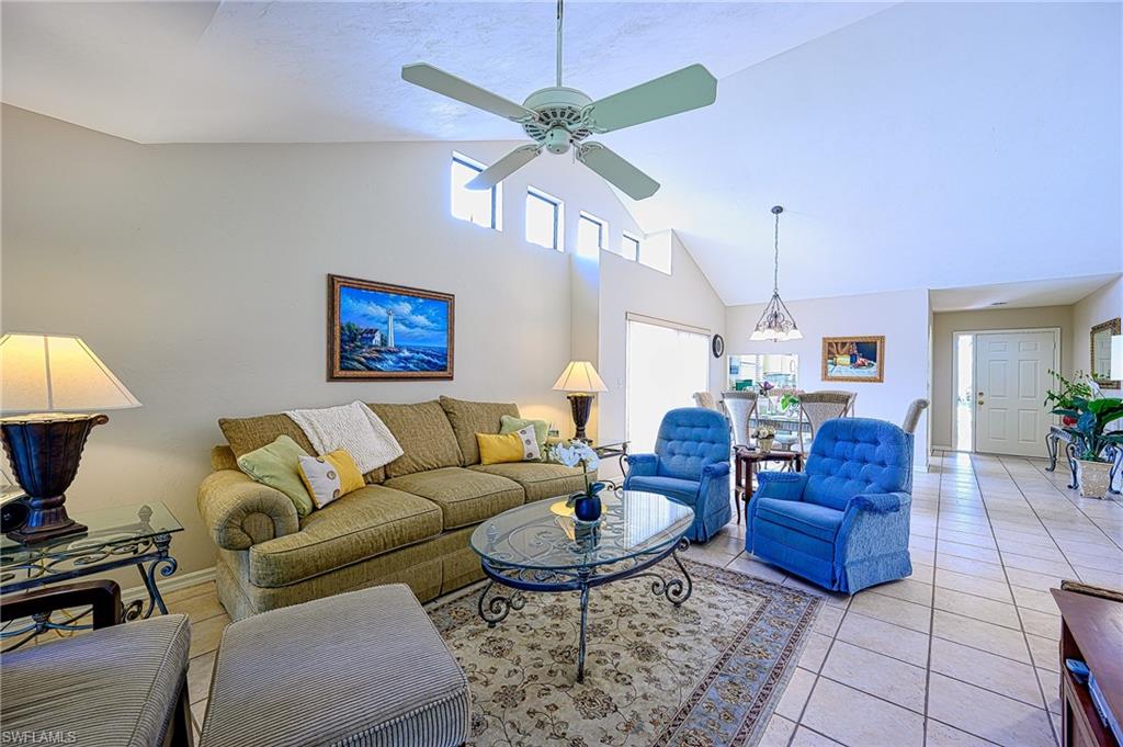 Living room with ceilingchandelier, light tile patterned flooring, and high vaulted ceiling
