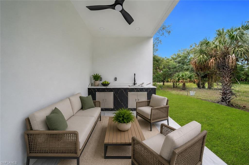 Covered patio featuring a built-in outdoor kitchen with a dark counter, a black faucet, and recessed lighting