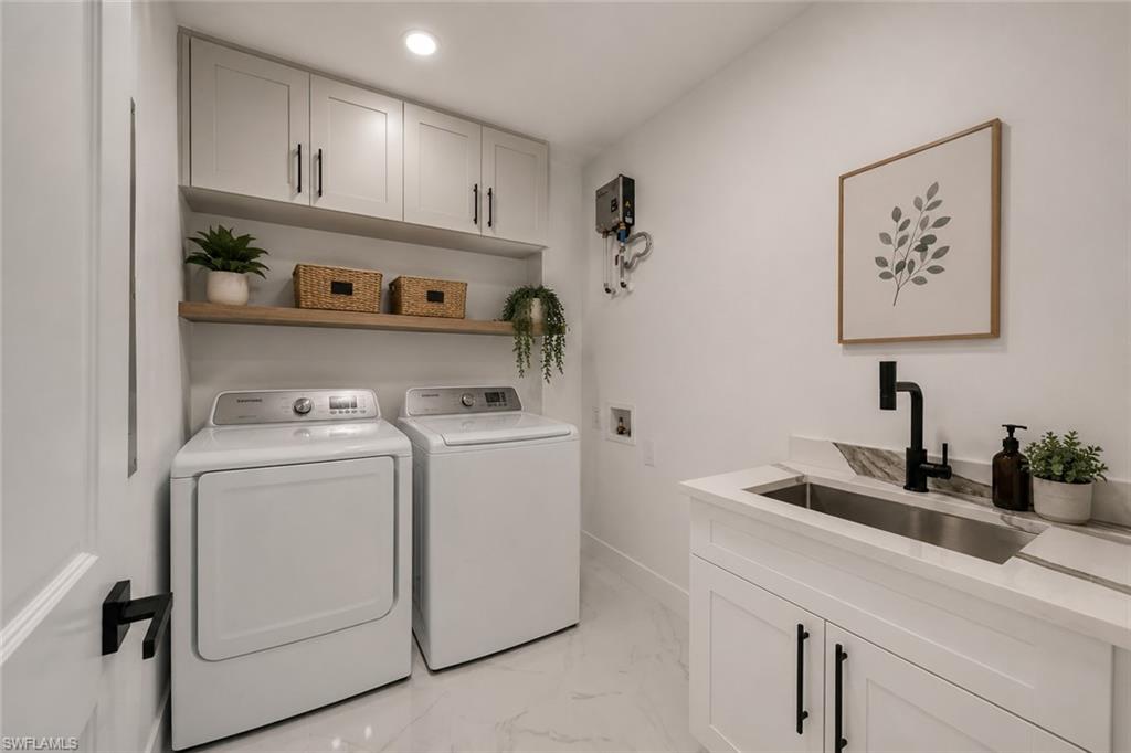 Dedicated laundry area featuring a utility sink with a black faucet, white cabinetry with black hardware, and an open wood-finish shelf