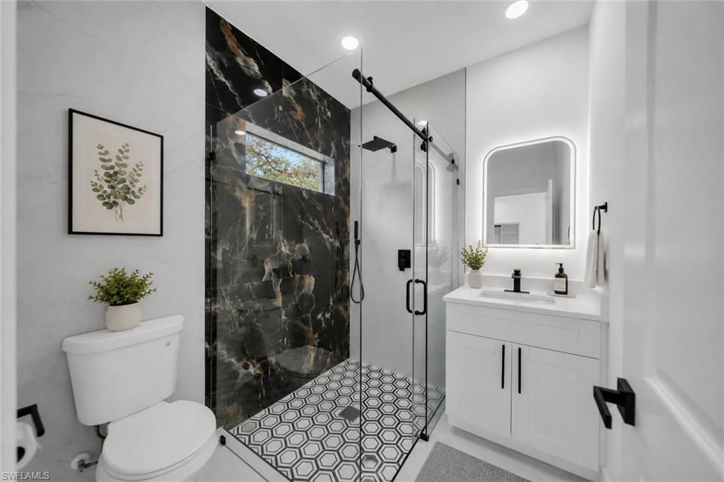 Modern bathroom featuring a walk-in shower with black-veined wall tile, hexagonal floor tile, and a glass enclosure