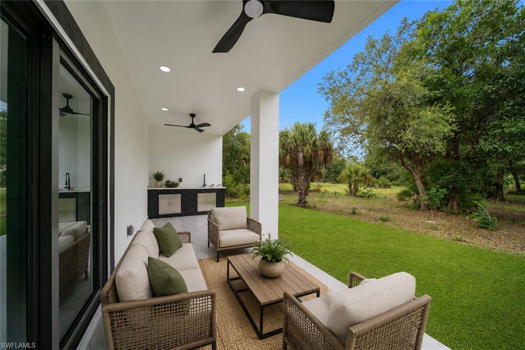 Covered patio featuring an outdoor kitchen with integrated sink, black countertops, and stainless steel cabinetry