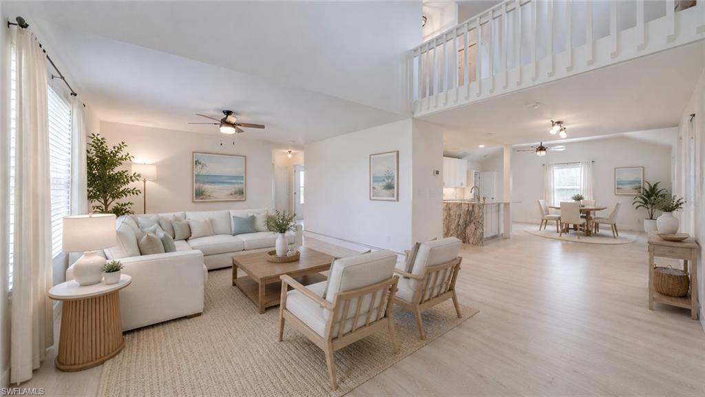Virtual - Spacious open-concept interior featuring light wood-finish flooring and vaulted ceilings
