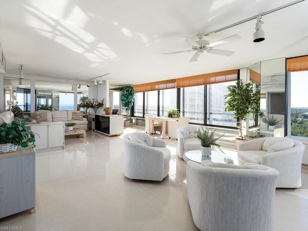 Tiled living room featuring ceiling fan, a wall of windows, and a healthy amount of sunlight