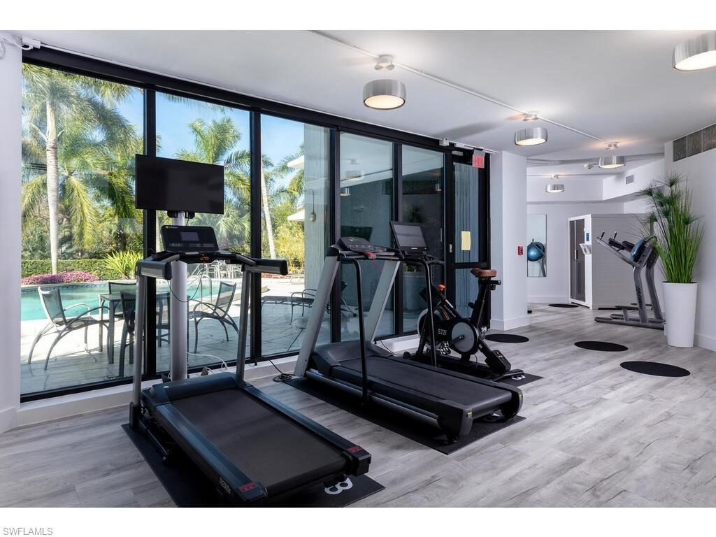Gym featuring expansive windows, wood-type flooring, and a healthy amount of sunlight