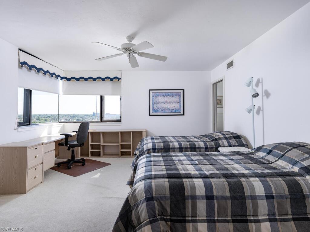 Carpeted bedroom with ceiling fan and built in desk