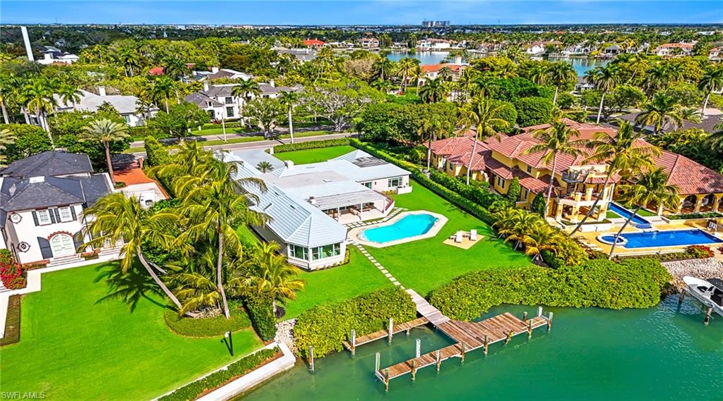 Aerial perspective of suburban area featuring a nearby body of water and a pool area