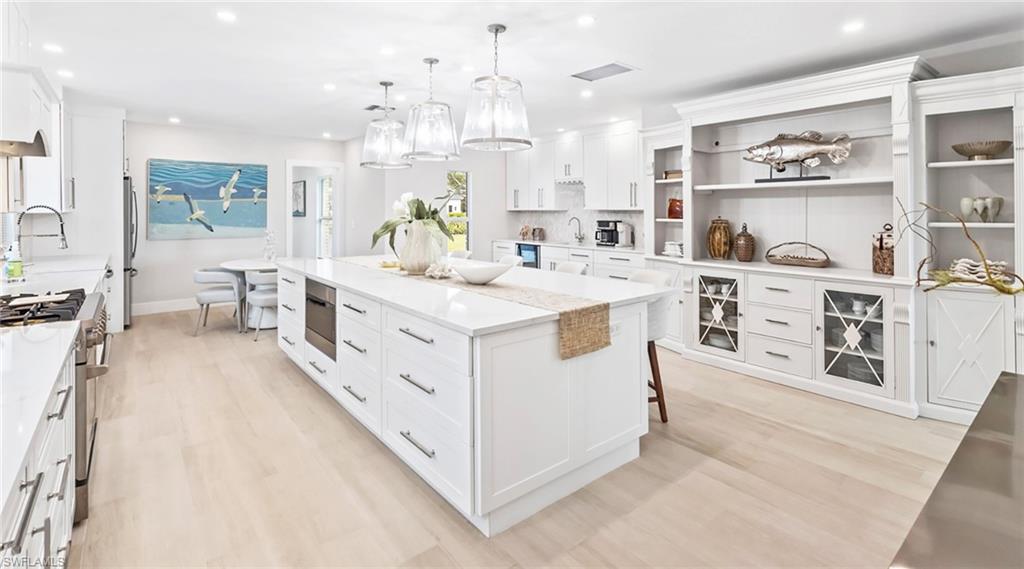 Kitchen featuring white cabinetry, hanging light fixtures, stainless steel appliances, and light wood-style floors
