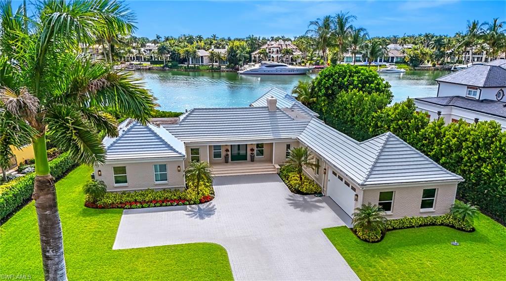 View of front of property featuring a water view, driveway, a garage, a front lawn, and a residential view