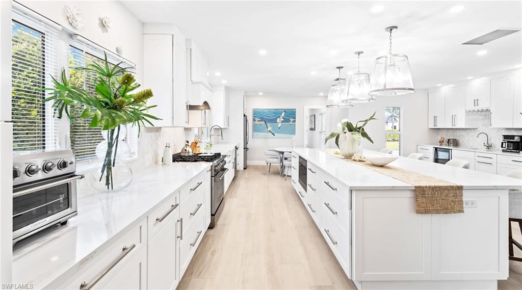 Kitchen with white cabinetry, backsplash, a breakfast bar area, and hanging light fixtures