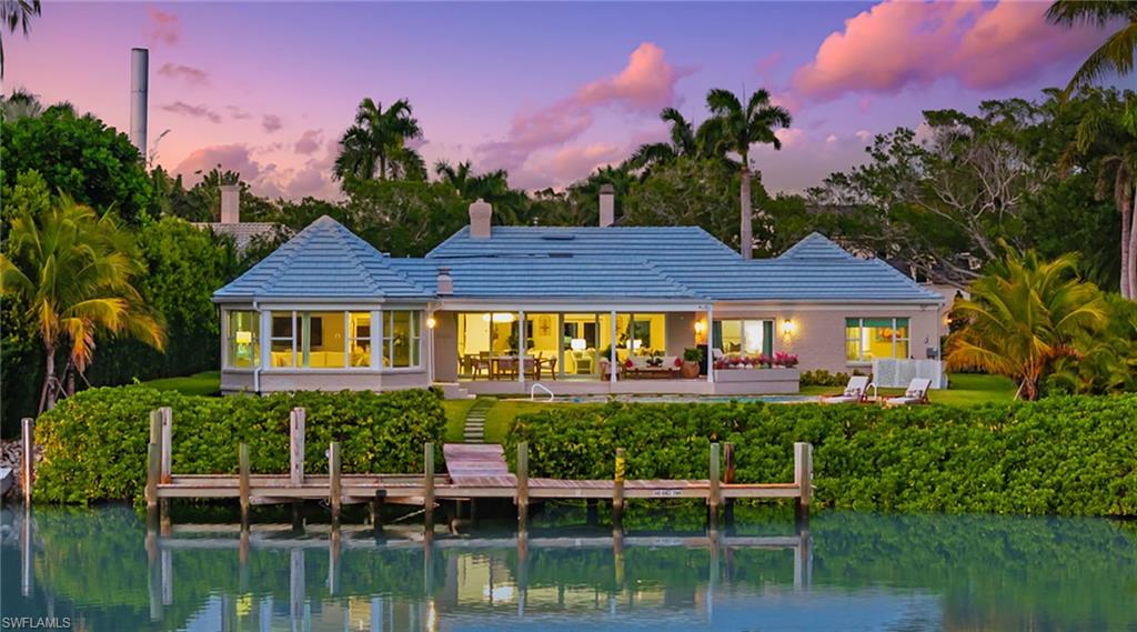 Back of house with a chimney, a water view, and a patio