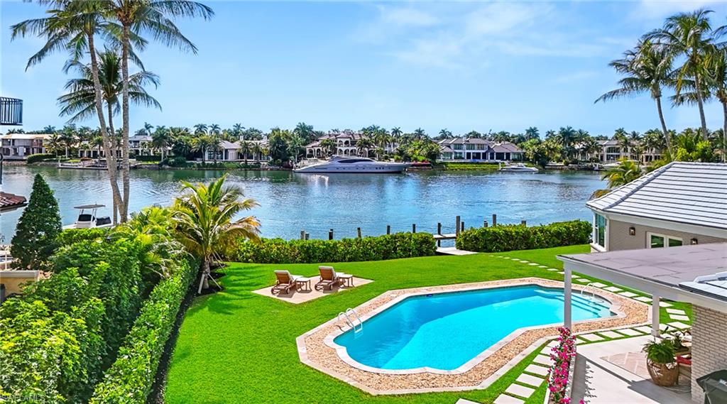 Outdoor pool featuring a patio, a yard, a water view, and a residential view