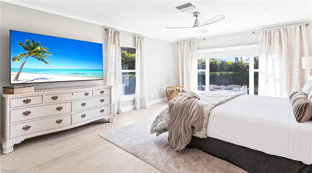 Bedroom with light wood finished floors, ceiling fan, and ornamental molding
