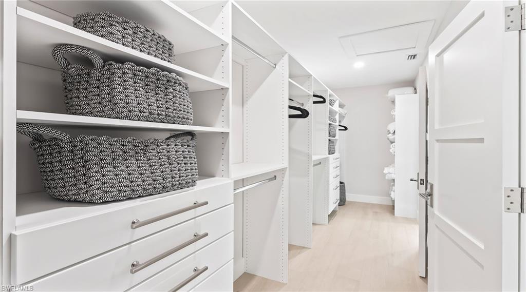 Walk in closet with attic access and light wood-style floors