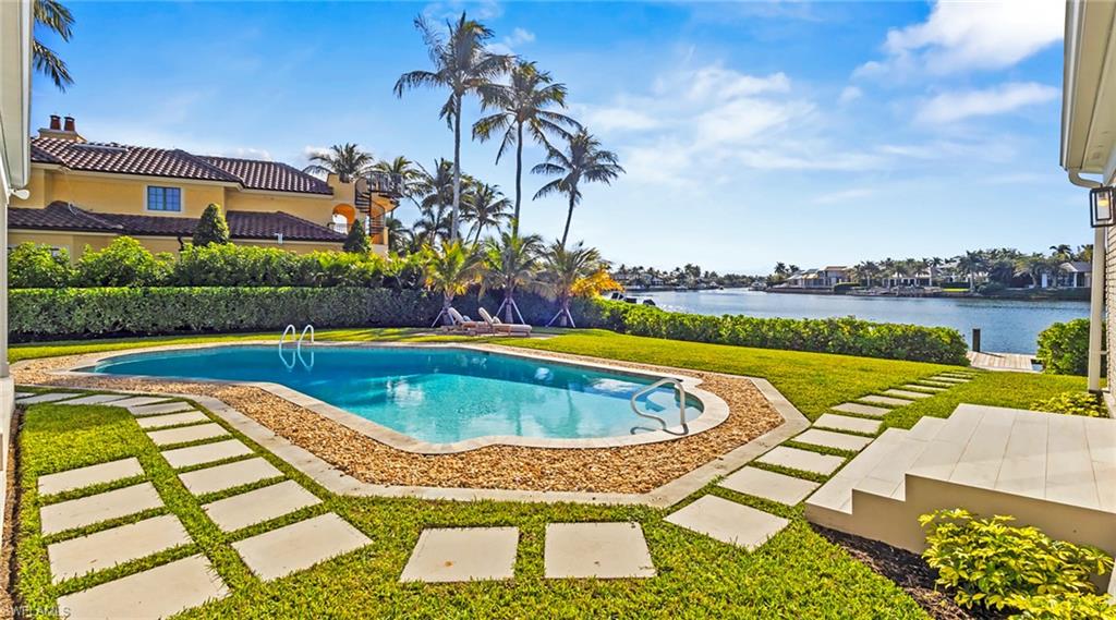 View of swimming pool featuring a yard, patio surround, and a water view