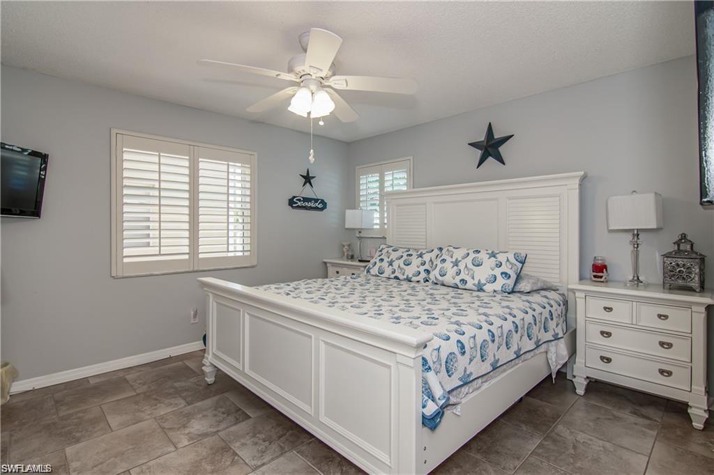 Spacious primary bedroom with tile flooring, plantation shutters, and coastal-inspired décor.