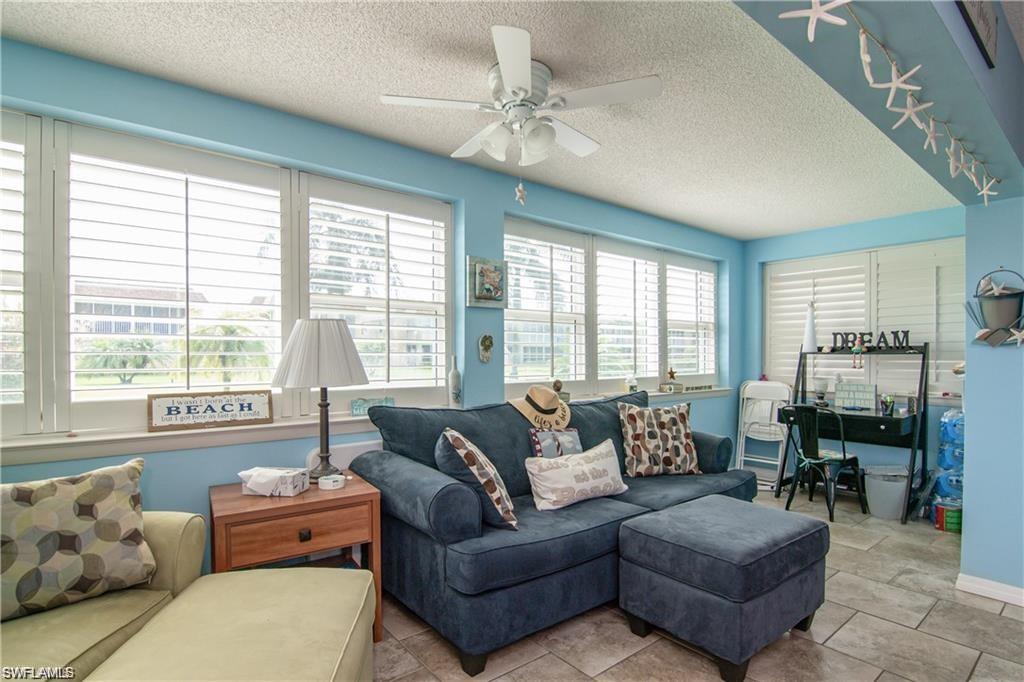 Bright sunroom featuring multiple windows with plantation shutters, a ceiling fan, and tile flooring