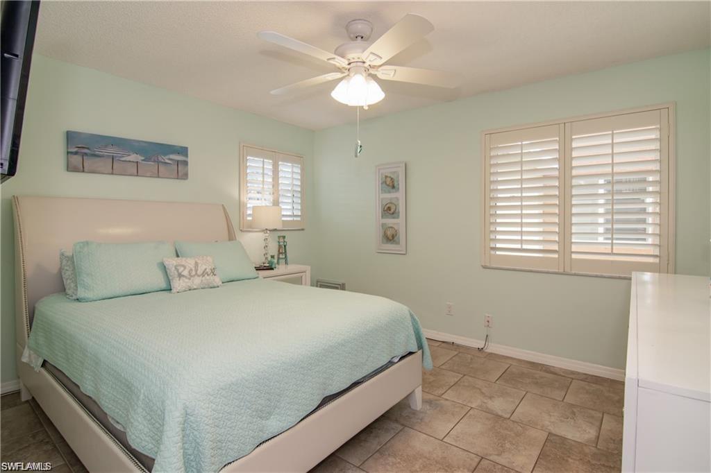 Guest bedroom with tile flooring, plantation shutters, and natural light.