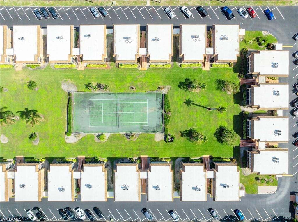 Community tennis court surrounded by landscaped grounds.