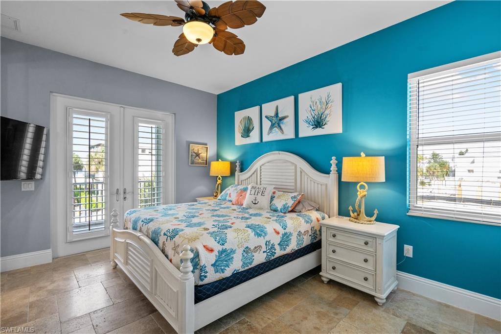 Bedroom featuring a vibrant accent wall, tile flooring, a ceiling fan, and French doors with plantation shutters