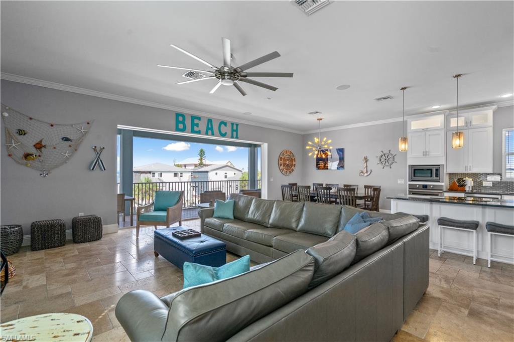 Spacious open-concept living area featuring large format tile flooring, a ceiling fan, and built-in lighting