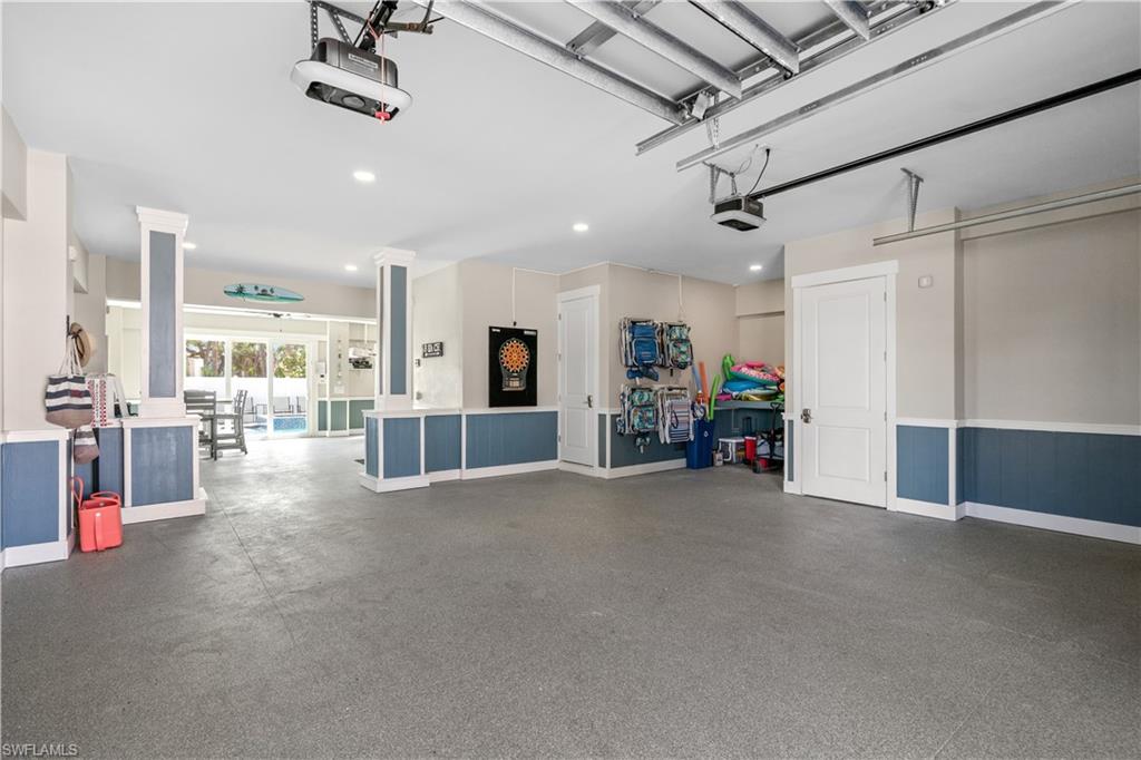 Spacious garage featuring a finished gray floor and blue wainscoting