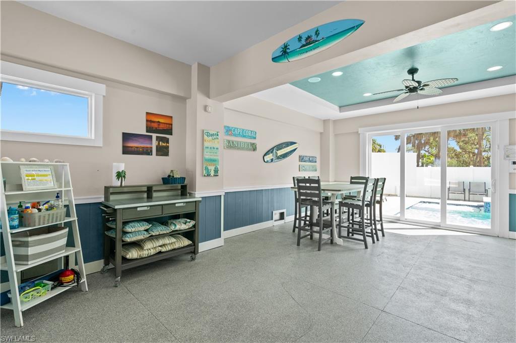Spacious indoor-outdoor living area featuring durable flooring, a vaulted ceiling with recessed lighting and a ceiling fan, and large sliding glass doors opening to a private pool area