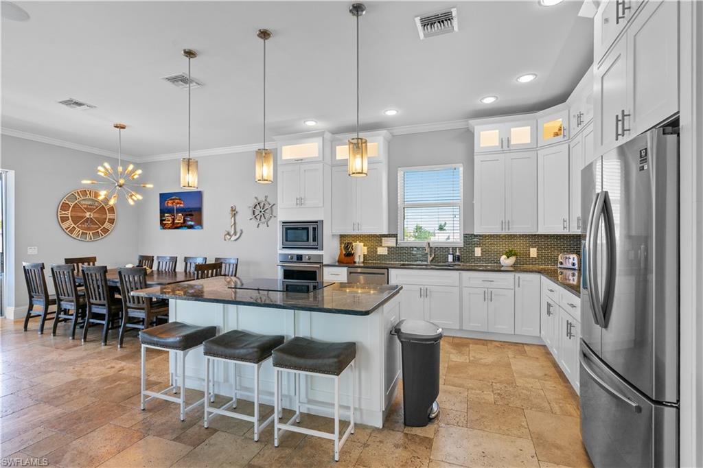 Spacious kitchen featuring white cabinetry, granite countertops, stainless steel appliances, a tiled backsplash, and recessed lighting