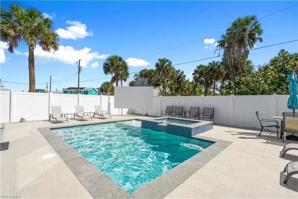 Outdoor entertainment area featuring an in-ground swimming pool, an integrated spa with blue mosaic tiling, and extensive light-toned paver decking