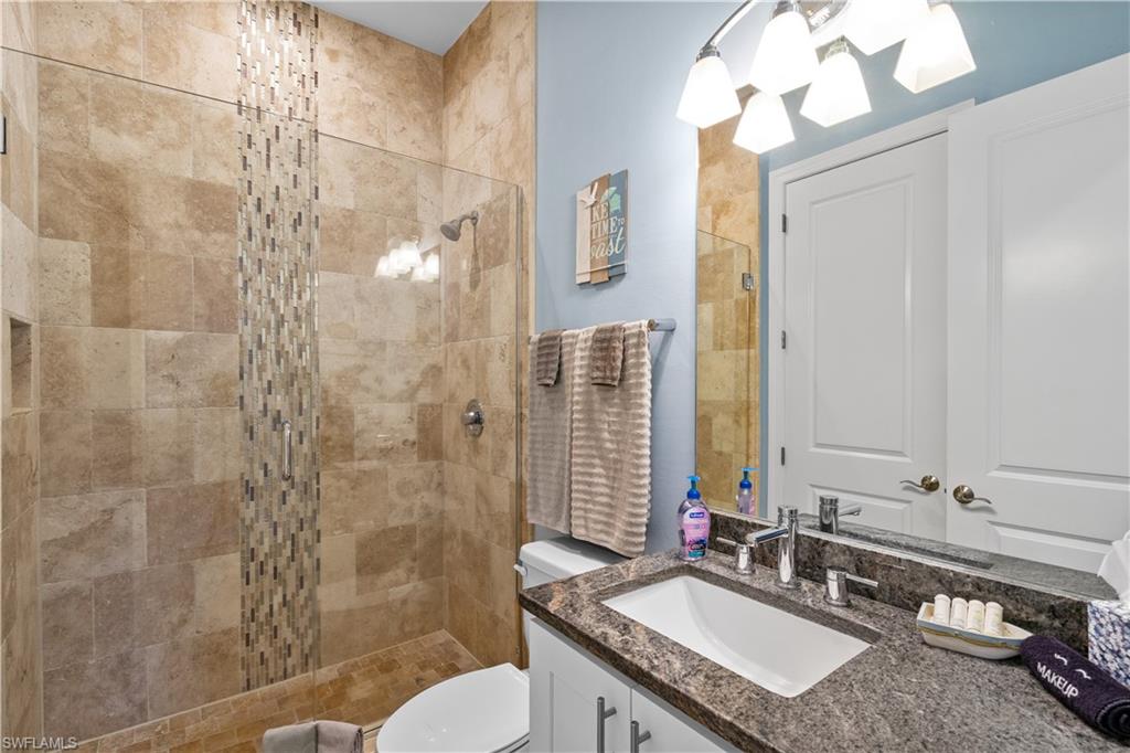Tiled shower enclosure with glass panel, integrated shower niche, and a mosaic accent strip