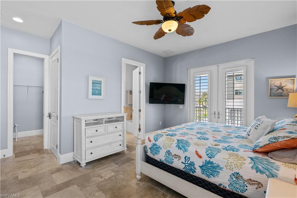Room featuring neutral tile flooring, light blue walls, and a ceiling fan with leaf-shaped blades