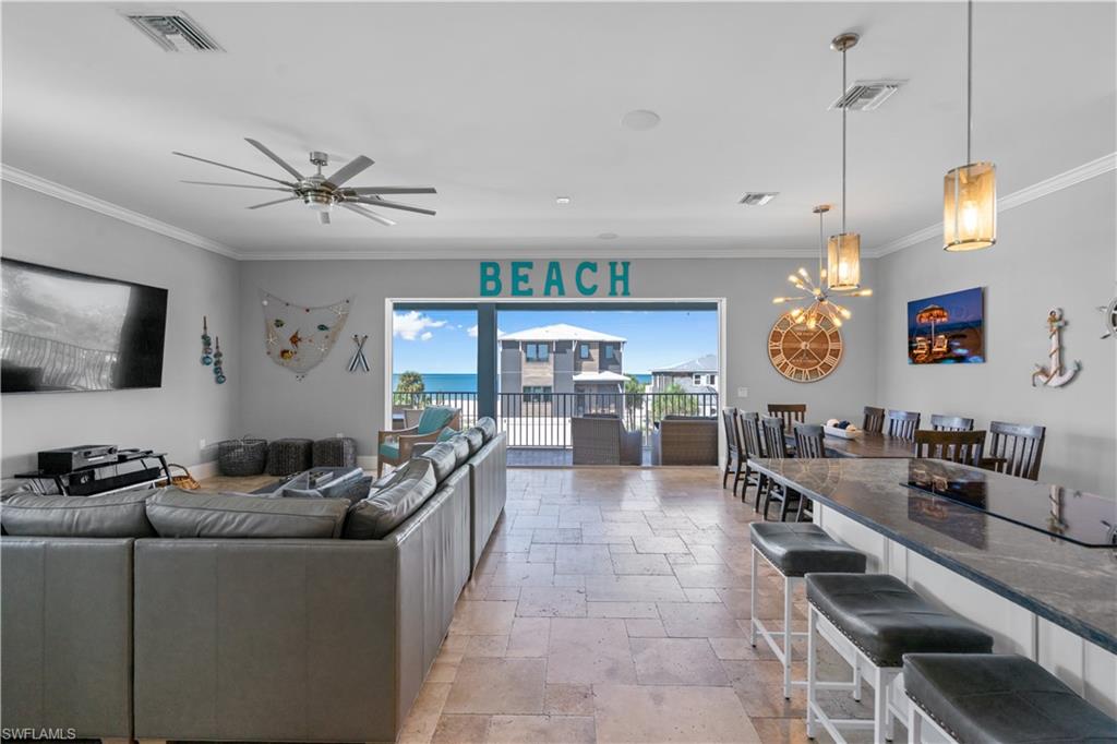 Spacious open-concept living area featuring stone tile flooring, crown molding, and recessed lighting