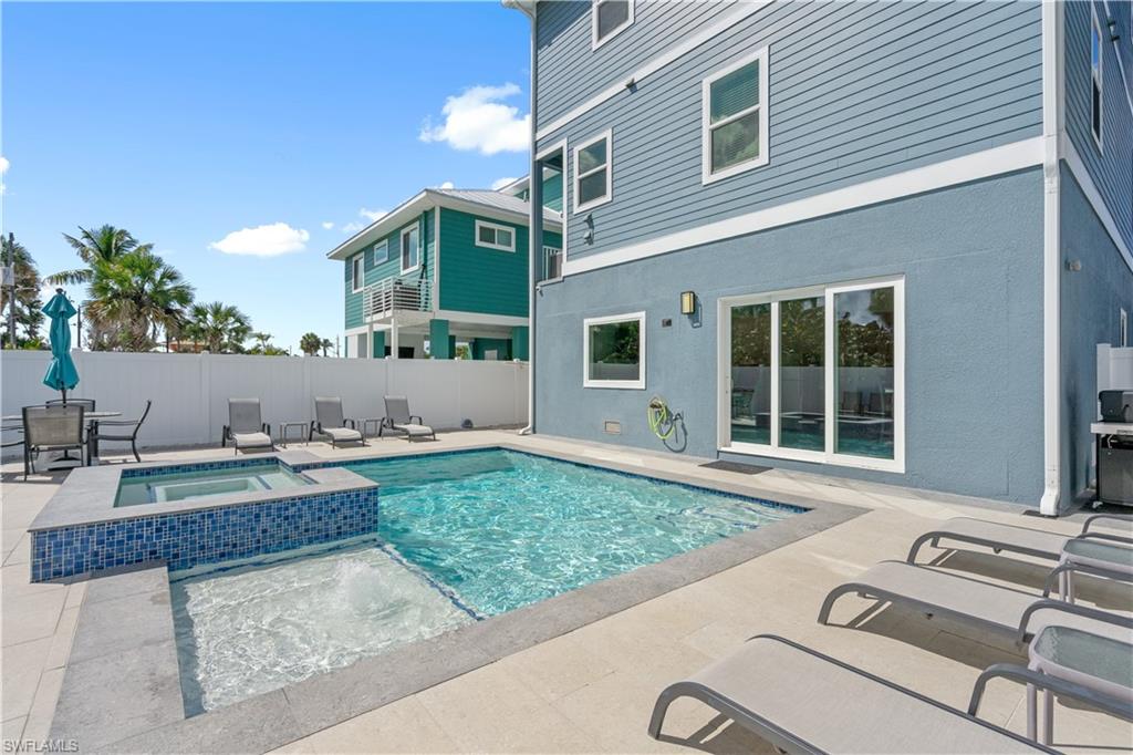 Private outdoor space featuring a swimming pool, integrated hot tub, and paver patio