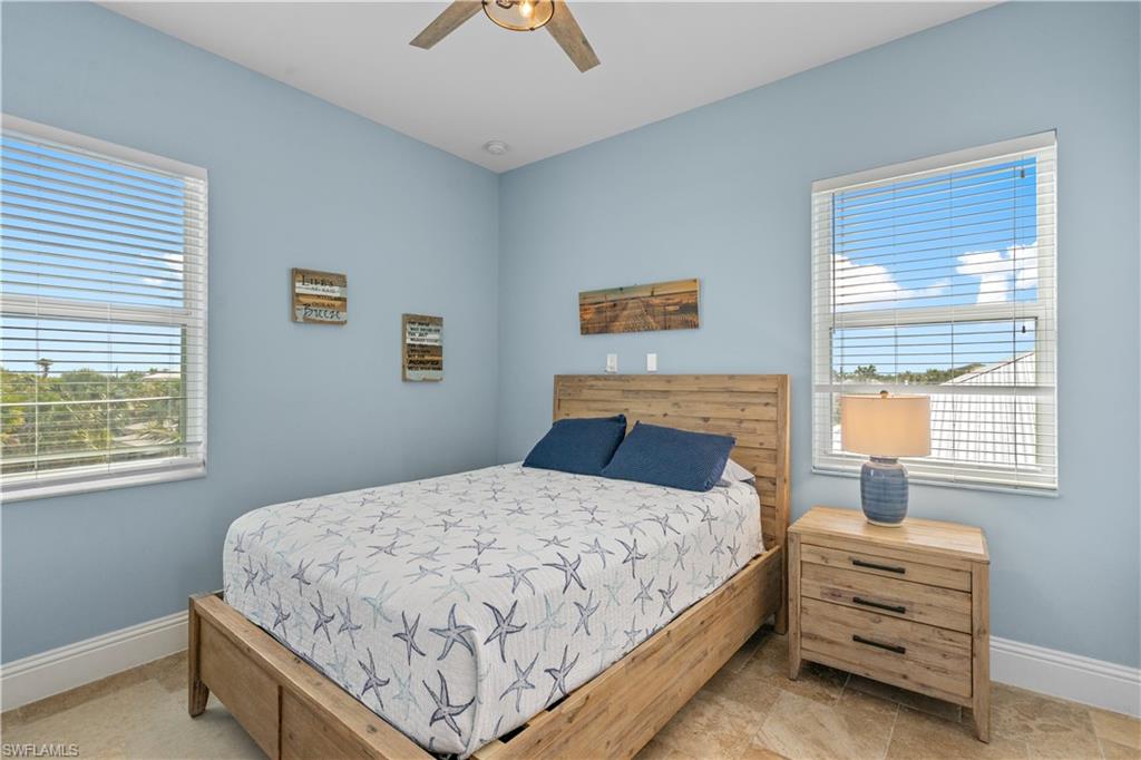 Spacious room featuring light blue walls, two large windows with blinds, and tile flooring