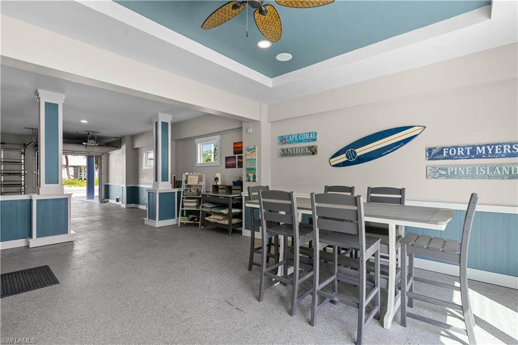 Spacious ground-level entertainment area featuring a decorative ceiling fan, recessed lighting, and a durable speckled floor finish