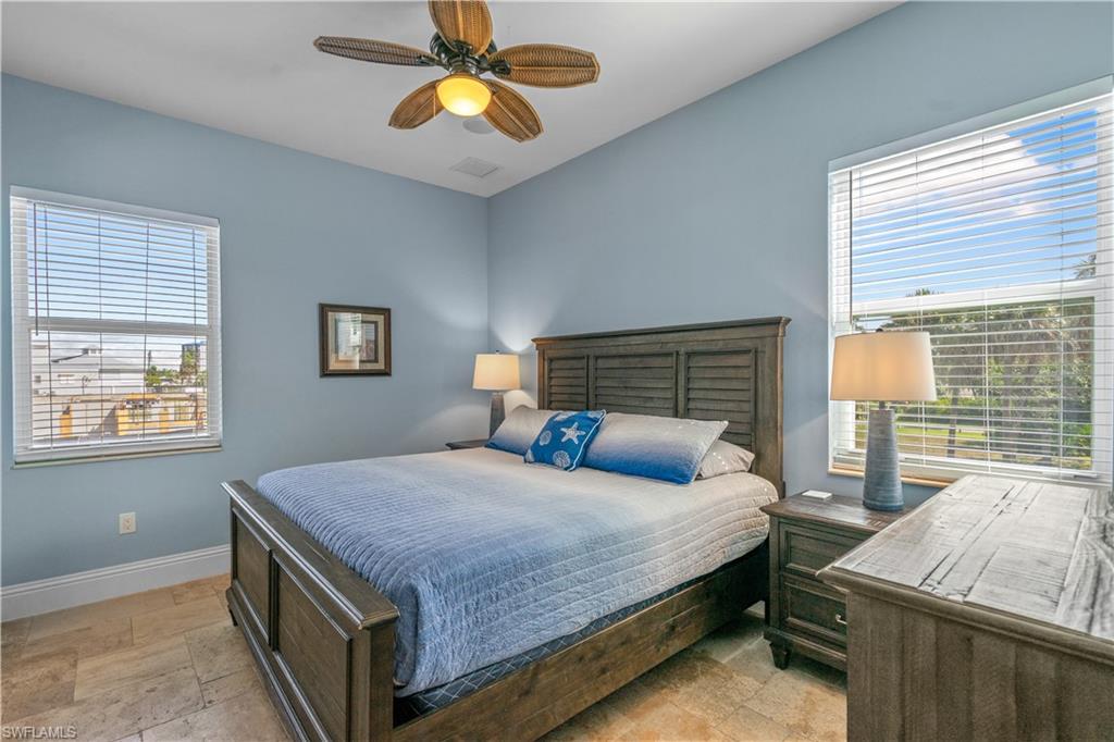Spacious room featuring vaulted ceilings, a ceiling fan, two windows with blinds, and tile flooring